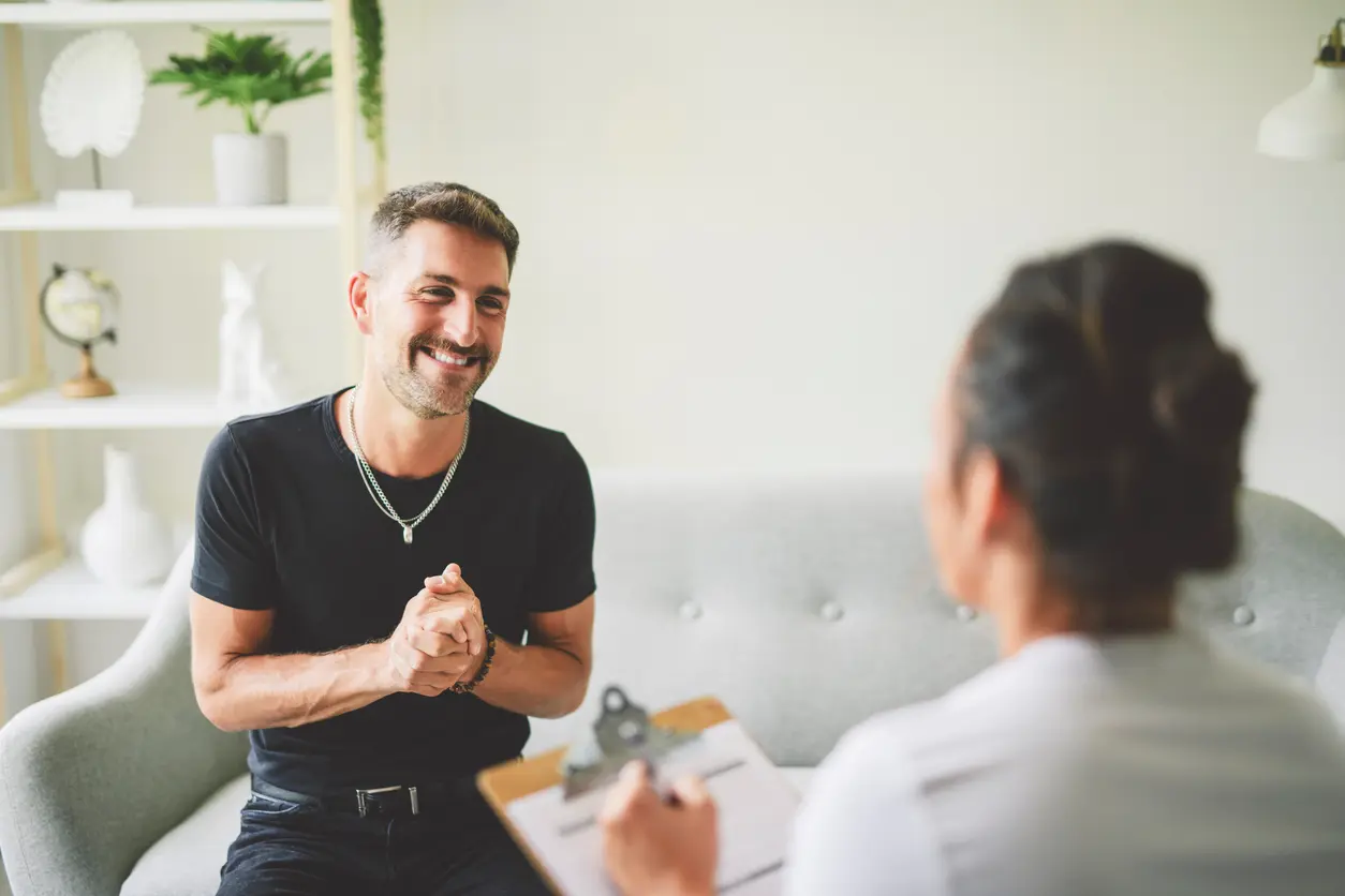 man talks to a woman while both are comfortably seated on a couch