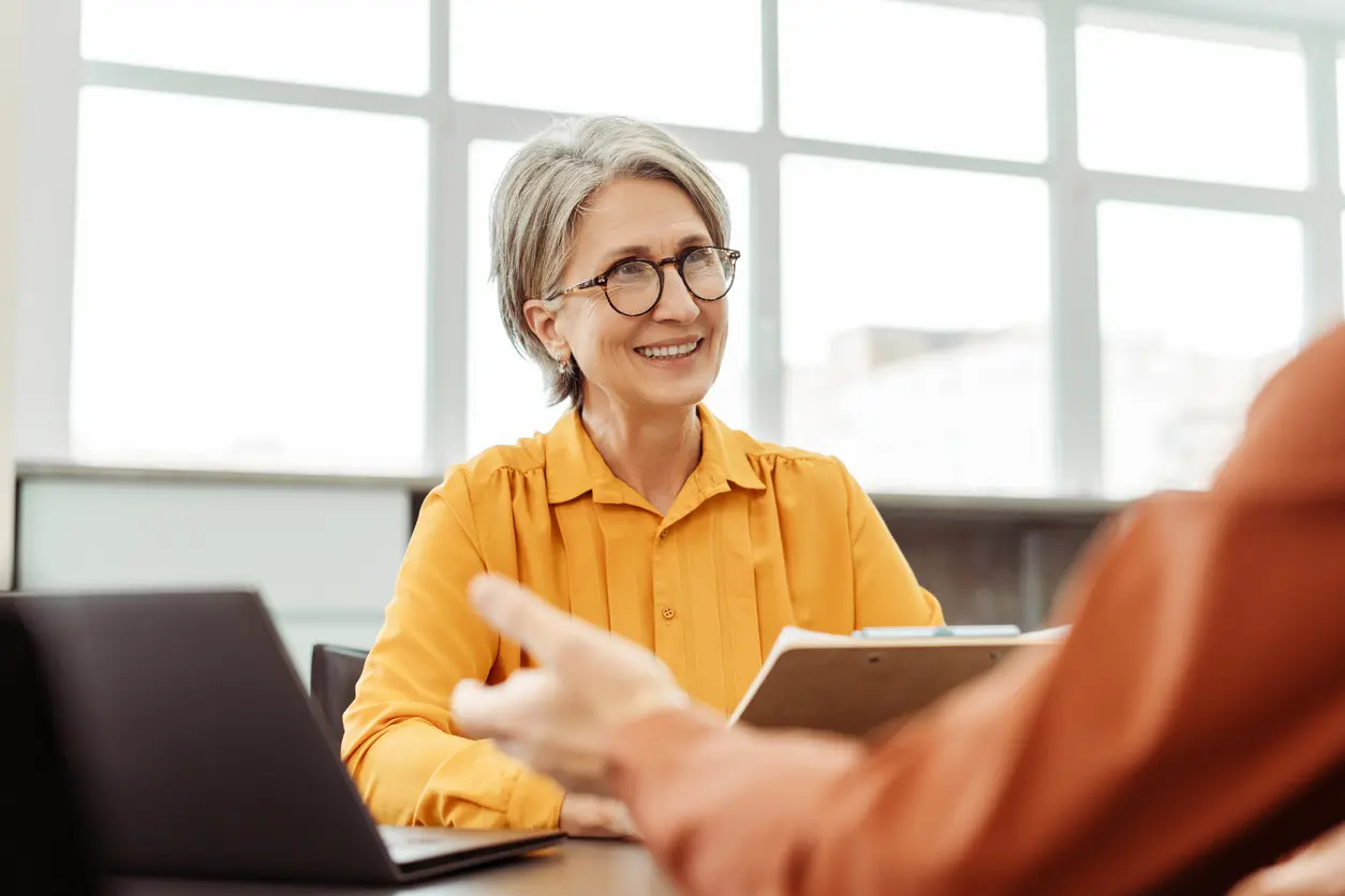 woman in glasses converses with a man at a table, engaged in a discussion