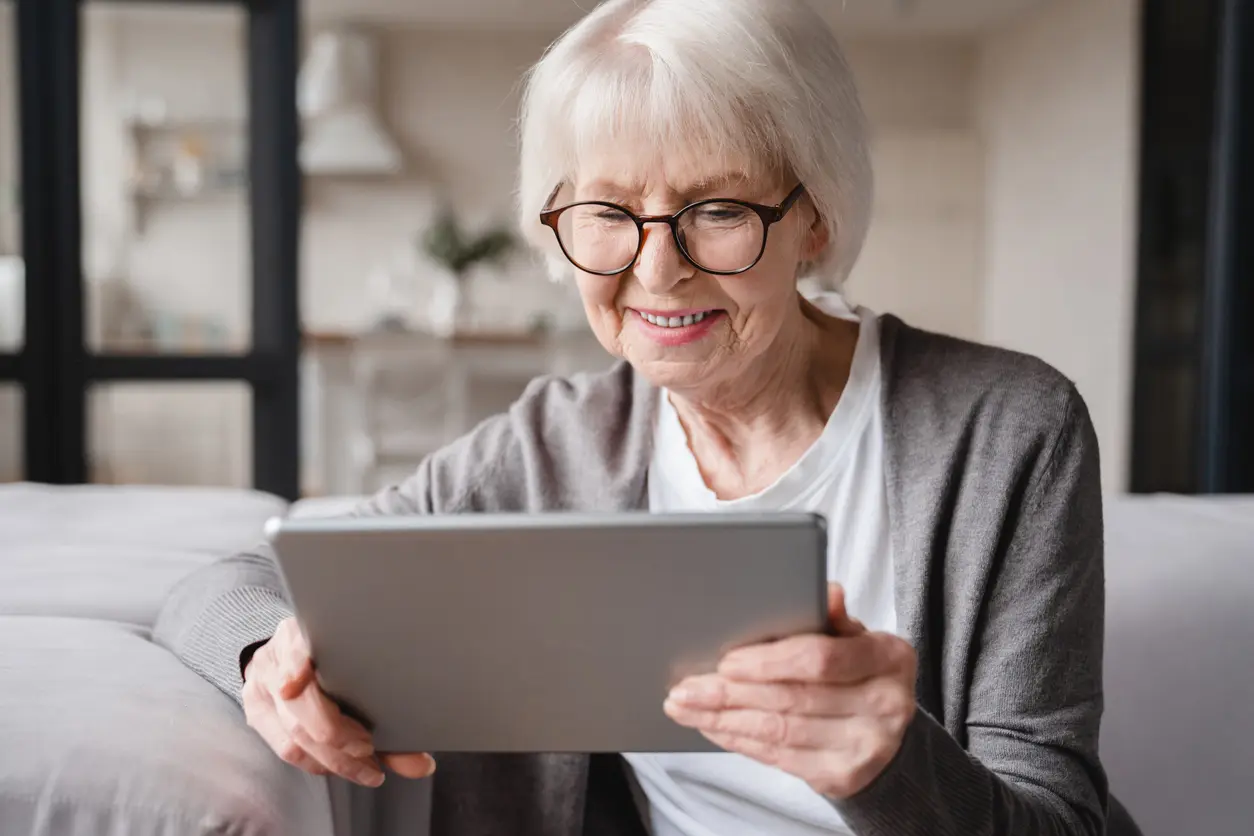 older woman with glasses intently using a tablet