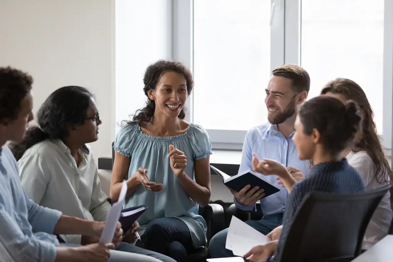 Several individuals seated at a table, actively talking and exchanging thoughts in a collaborative setting