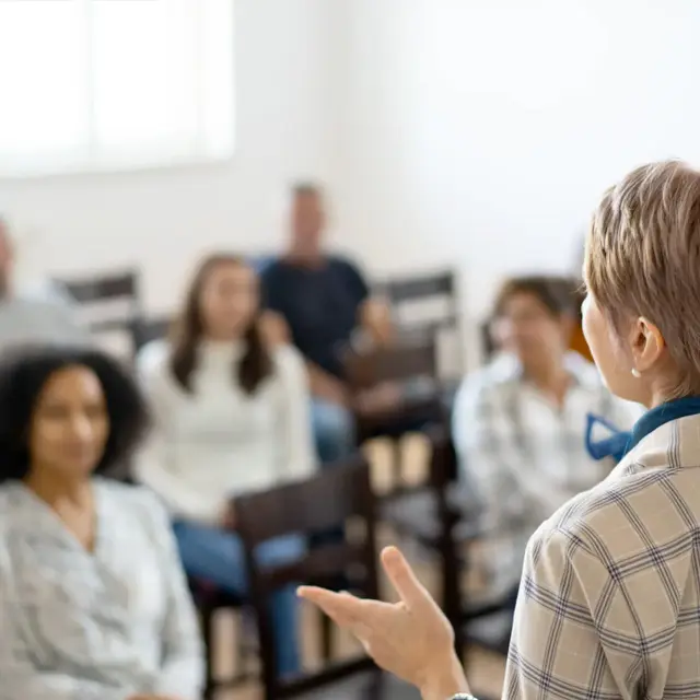 woman delivers a presentation to a captivated group of listeners in a conference setting