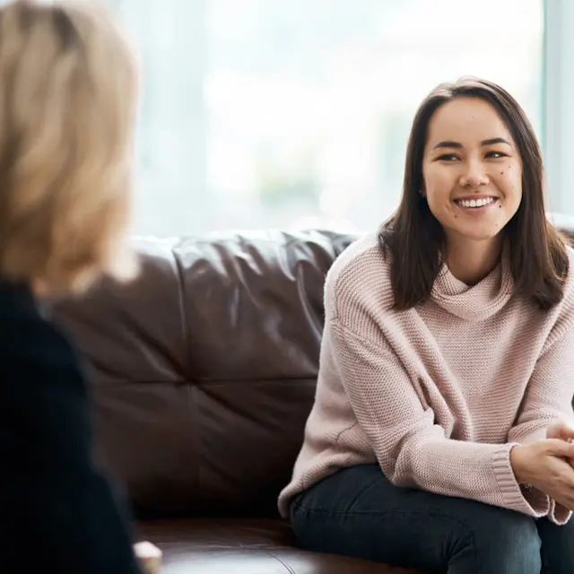 woman converses with another woman while sitting on a couch